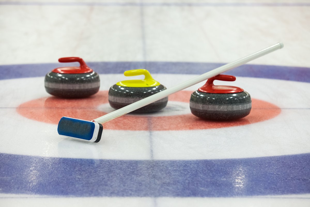Image of a curling stones and brooms on ice