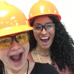 Clair and Courtney wearing hard hats and safety glasses smiling at the camera