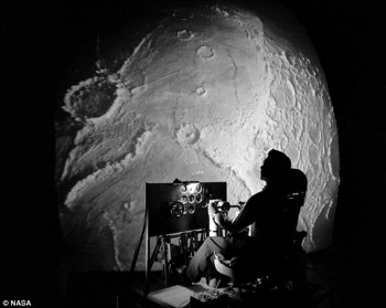 Large image of the Moon with a person in a chair looking at the image and a computer screen