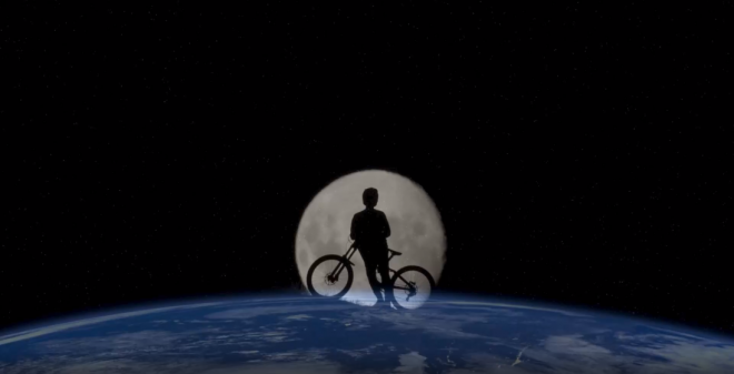 Image of the earth from space with the moon behind it and peaking out above Earth with a silhouette of a child and a bike in the image of the Moon.